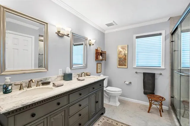 a bathroom with a granite countertop double vanity sink mirror and toilet
