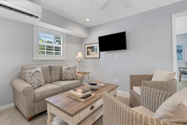 a living room with furniture a flat screen tv and a window