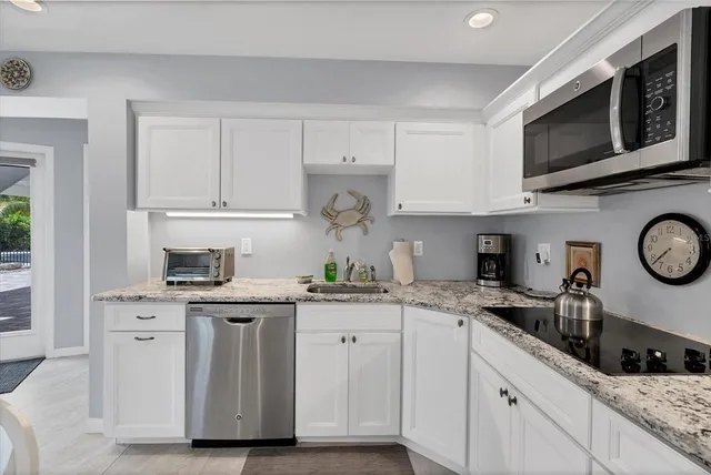 a kitchen with stainless steel appliances granite countertop a sink a stove a microwave and cabinets