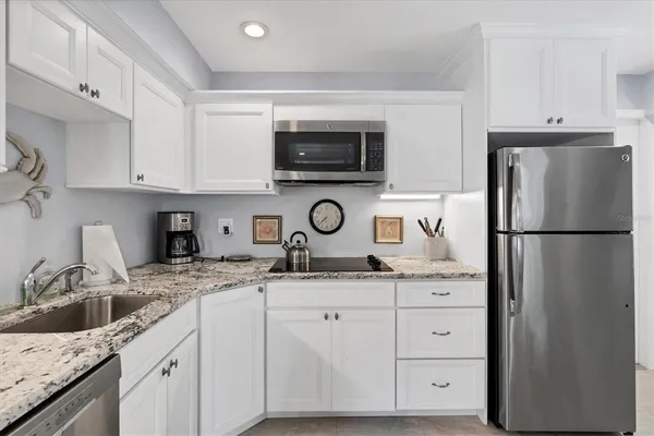 a kitchen with granite countertop a sink and a refrigerator