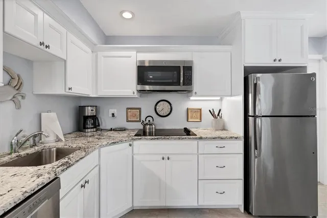 a kitchen with granite countertop a sink and a refrigerator