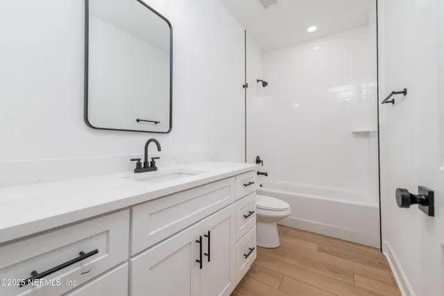 a bathroom with a double vanity sink toilet mirror and bathtub