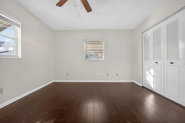 an empty room with wooden floor and windows