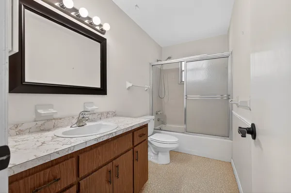 a bathroom with a granite countertop sink a toilet and a mirror