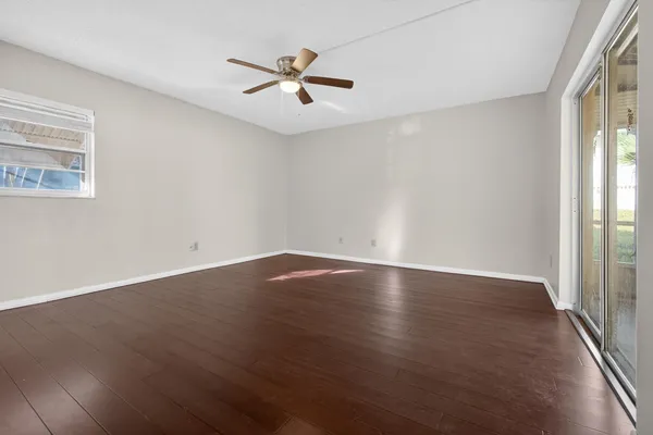 an empty room with wooden floor and windows