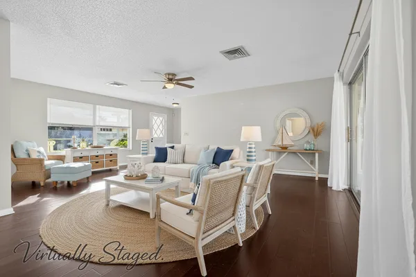 a living room with couches chairs and a dining table with wooden floor