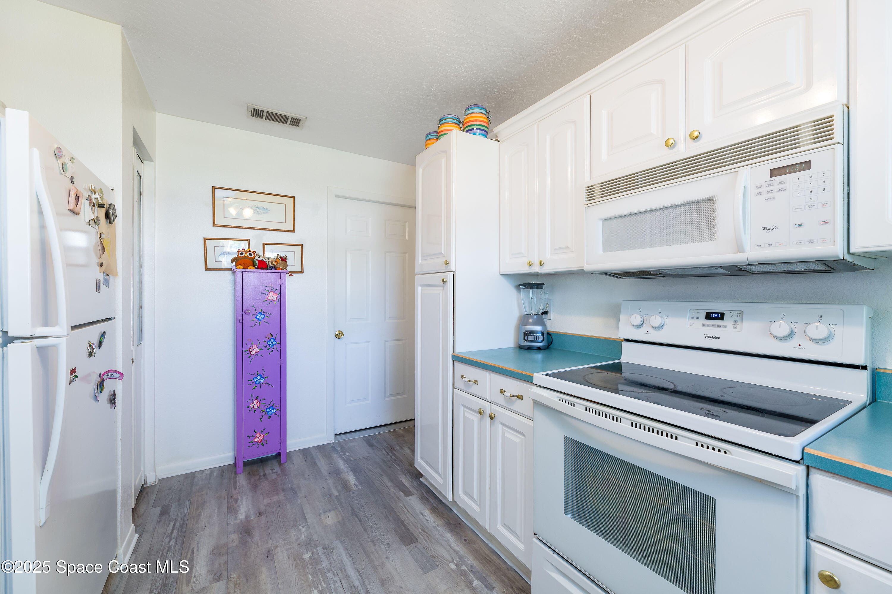 1135 Audubon Road Merritt Island, FL 32953 - Photo 15 of 52 a kitchen with stainless steel appliances white cabinets and wooden floors