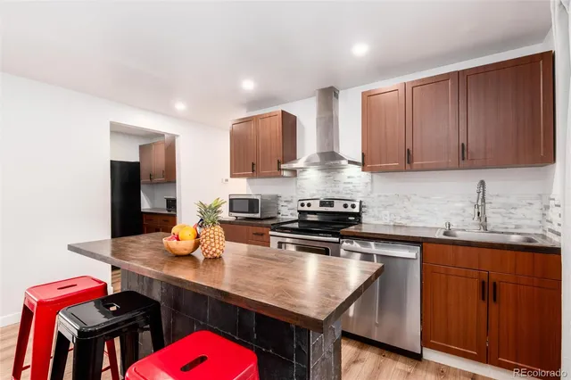 a kitchen with stainless steel appliances a sink a stove a refrigerator and wooden cabinets