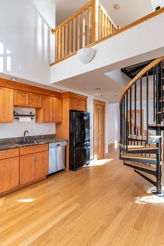 a view of a kitchen with stainless steel appliances wooden floor and living room