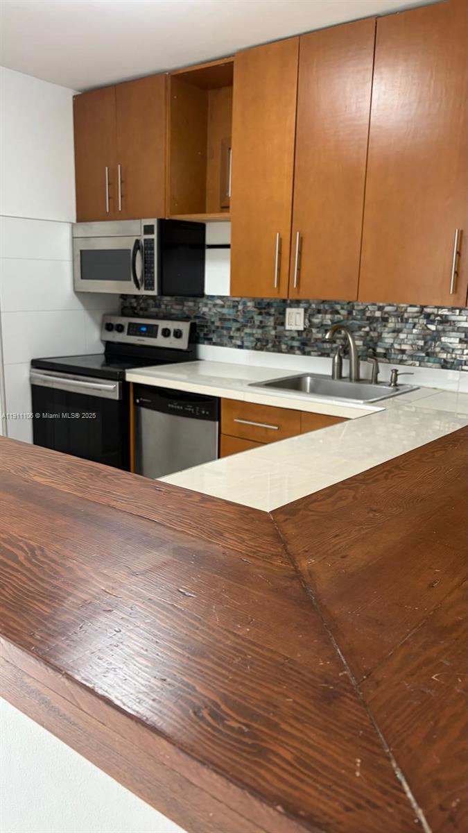 7925 Fairview Drive, Unit 110 Tamarac, FL 33321 - Photo 8 of 34 a kitchen with stainless steel appliances wooden cabinets and a counter top space