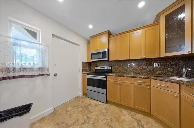 a kitchen with stainless steel appliances granite countertop a stove a sink and a microwave