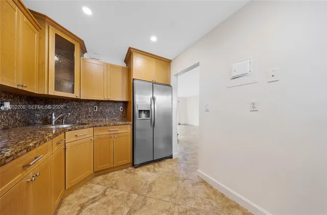 a bathroom with a granite countertop sink and a refrigerator