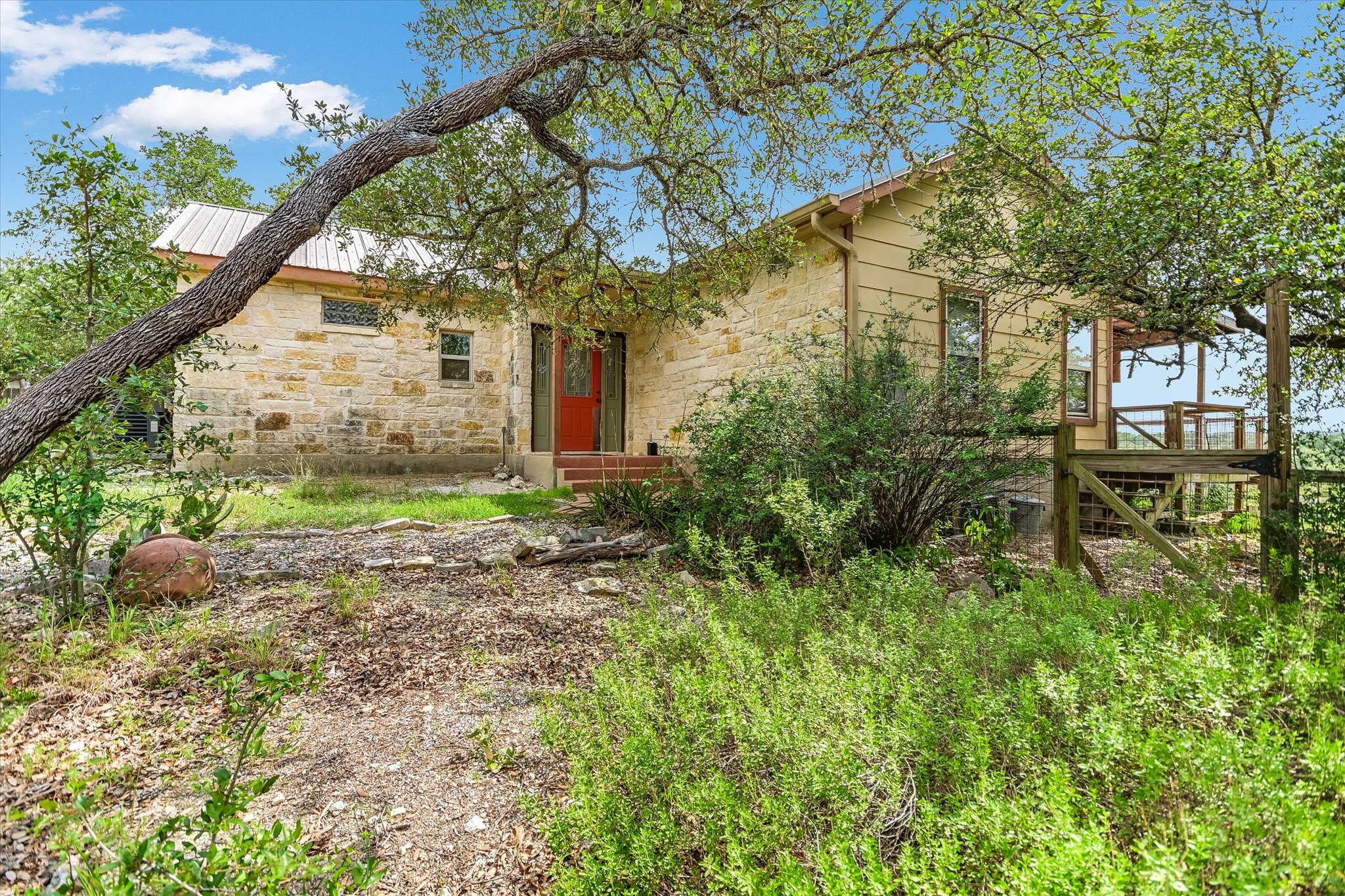 700 Cliffside Road Wimberley, TX 78676 - Photo 1 of 22 Stone-clad exterior featuring a metal roof and a vibrant red entry door