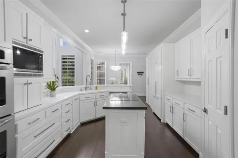 a kitchen with granite countertop white cabinets and black stainless steel appliances
