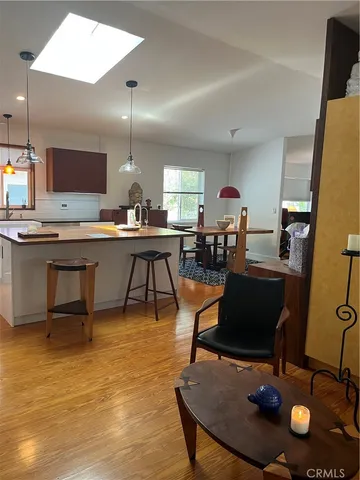 a room with stainless steel appliances granite countertop a sink dishwasher a dining table and chairs with wooden floor