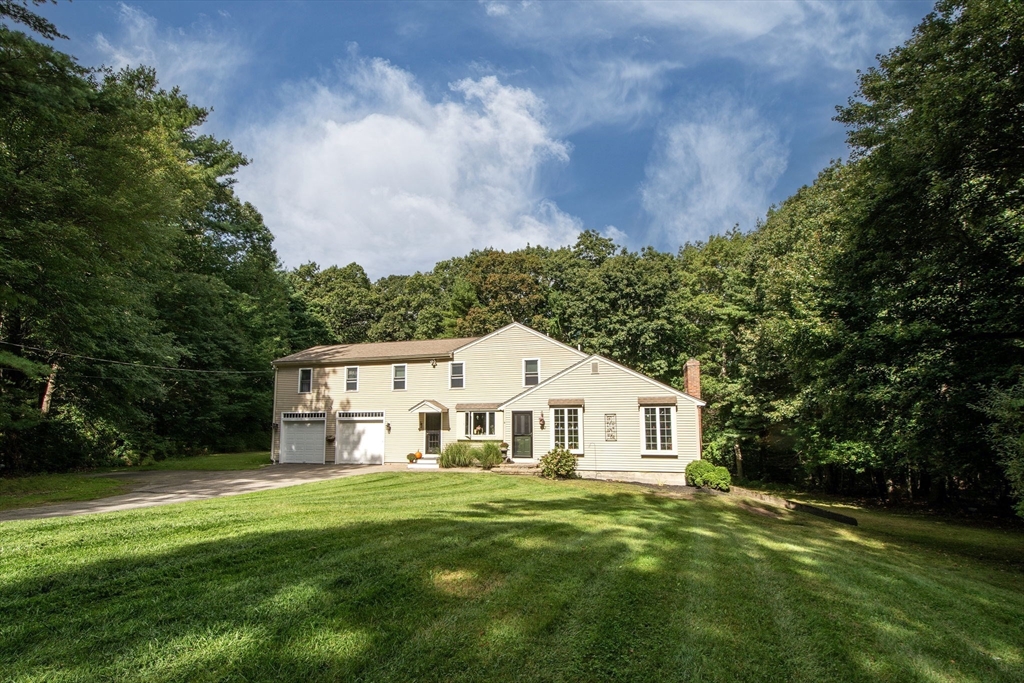a view of a white house with a big yard and large trees