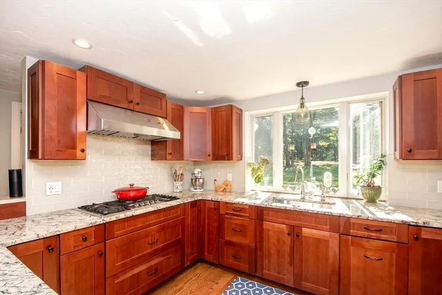 a kitchen with stainless steel appliances granite countertop wooden cabinets a sink and a large window