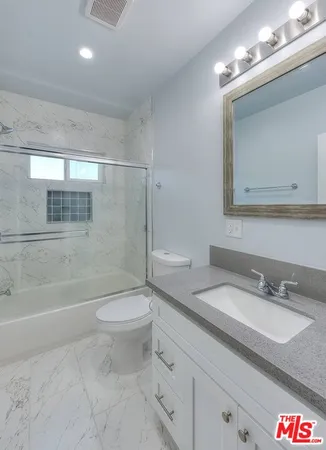 a bathroom with a granite countertop sink a toilet and shower