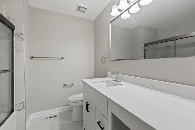 a bathroom with a sink a toilet and a mirror