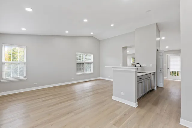 a large white kitchen with a sink wooden floor and stainless steel appliances