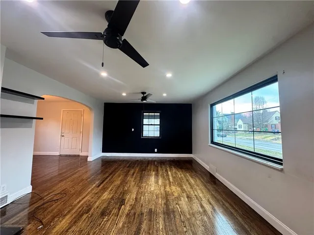 an empty room with a ceiling fan and window