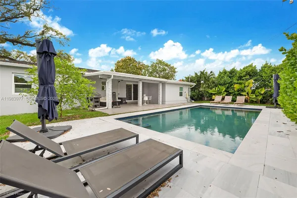 a view of house with swimming pool and yard