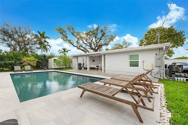 a view of a house with pool and chairs