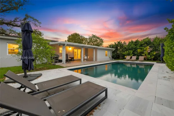 a view of house with swimming pool and a yard