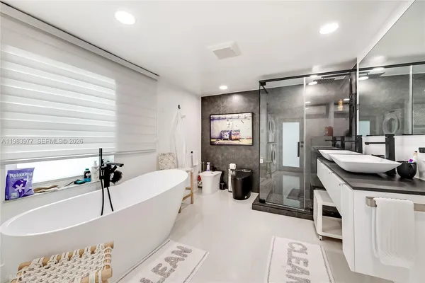 a bathroom with a tub a sink and a large mirror