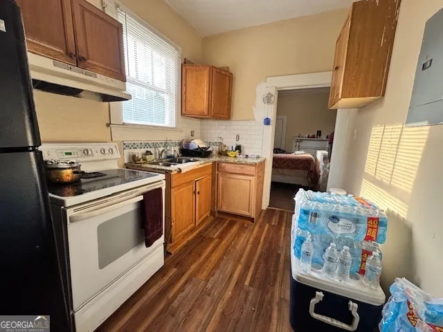 a kitchen with stainless steel appliances granite countertop a stove a sink dishwasher and white cabinets with wooden floor