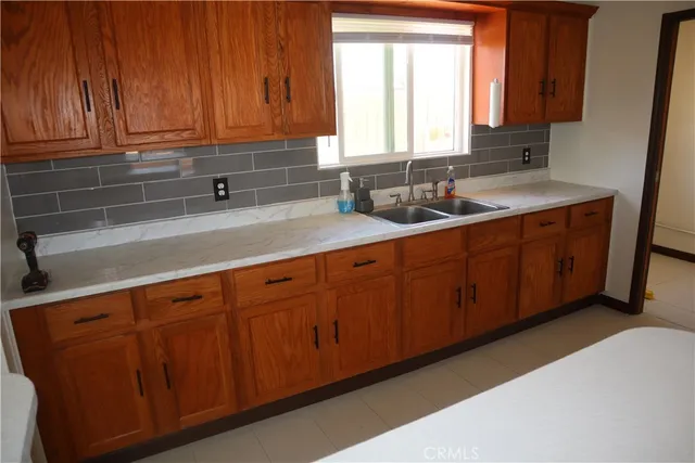 a kitchen with stainless steel appliances granite countertop a sink a washer and dryer with wooden cabinets