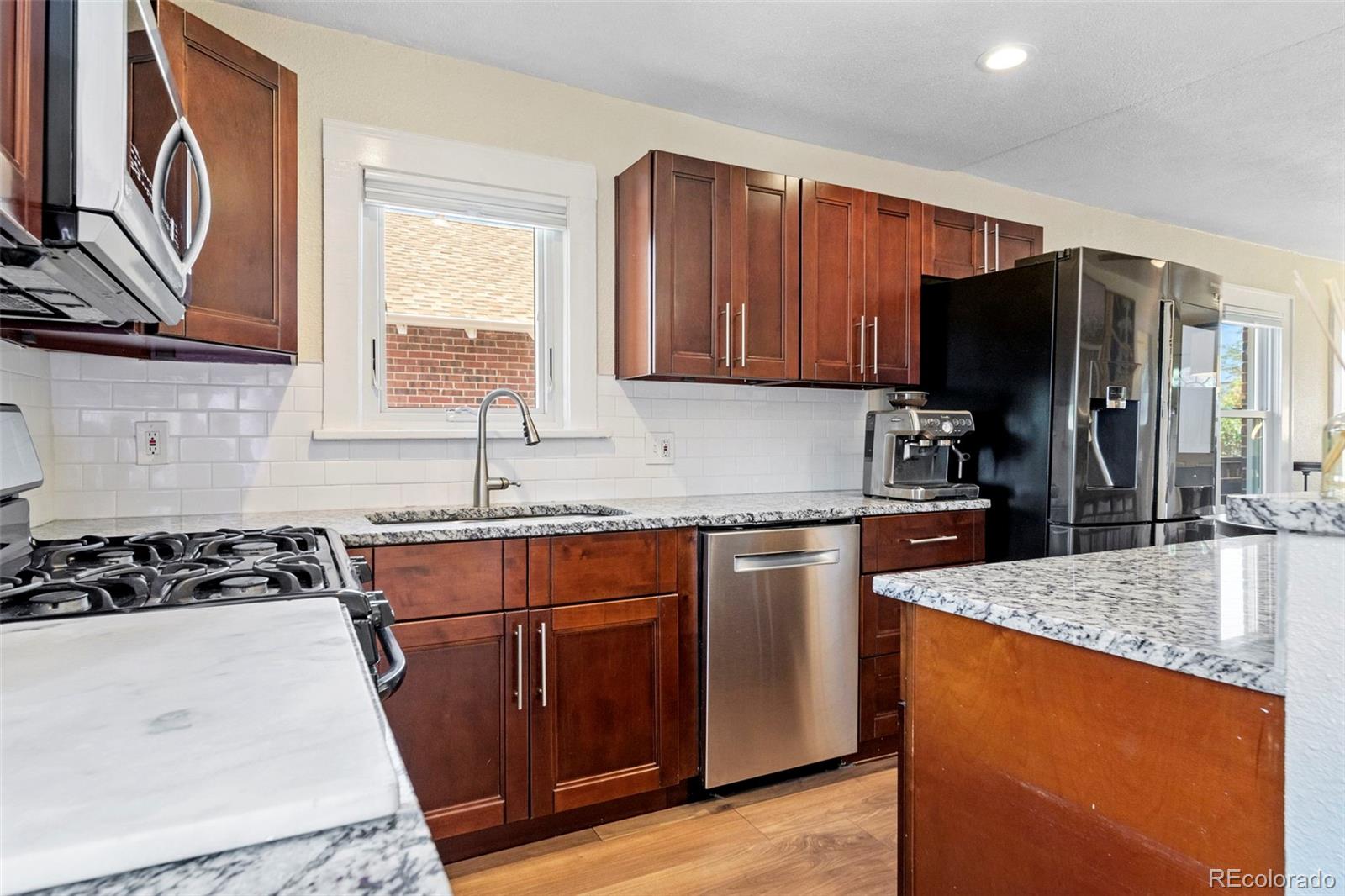 4319 Raritan Street Denver, CO 80211 - Photo 13 of 27 a kitchen with stainless steel appliances granite countertop a stove a sink dishwasher and a refrigerator with wooden cabinets