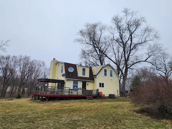 a view of a white house with a big yard and large trees