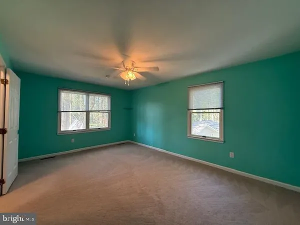 an empty room with a window and chandelier fan