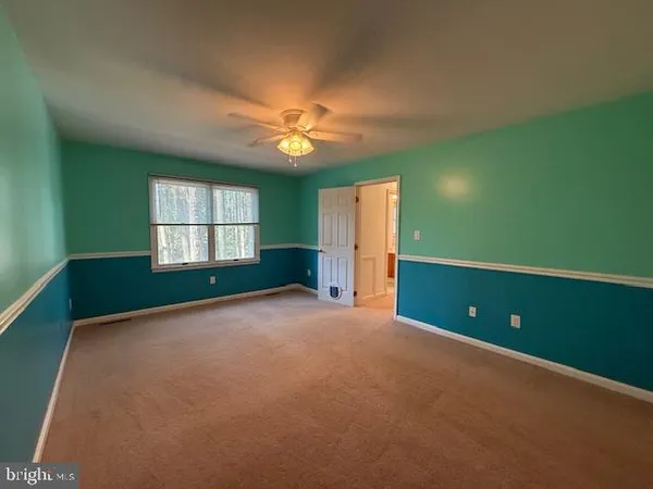 a view of an empty room with a window and a kitchen