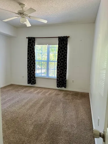 an empty room with windows and fan