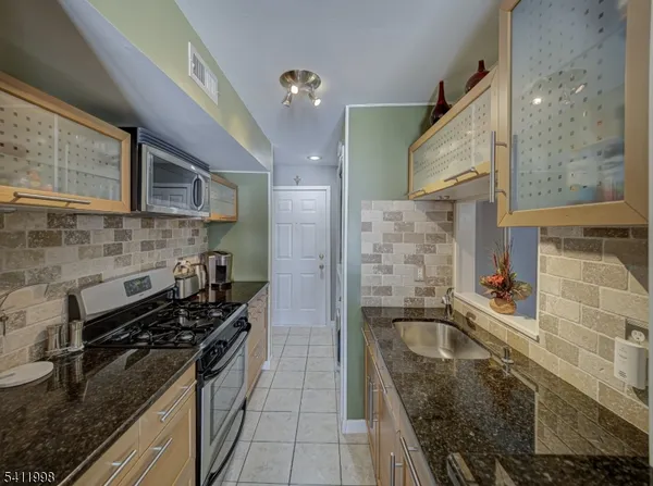 a kitchen with stainless steel appliances granite countertop a sink stove and cabinets