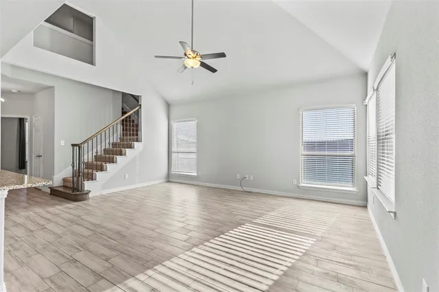 a view of an empty room with wooden floor and a chandelier