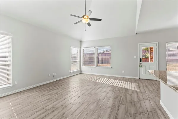 an empty room with wooden floor chandelier fan and windows
