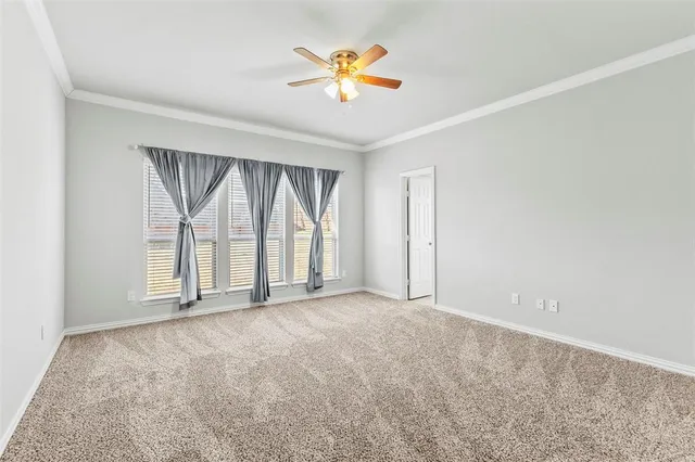 an empty room with chandelier fan and windows