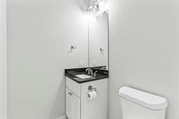 a bathroom with a granite countertop sink and a toilet