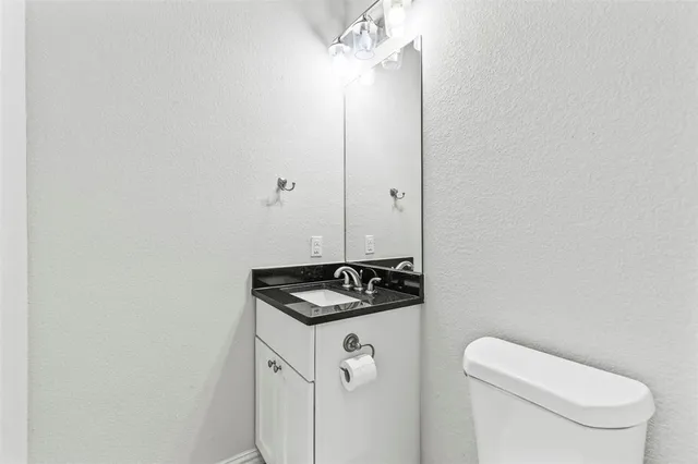 a bathroom with a granite countertop sink and a toilet