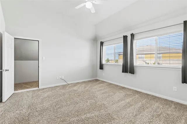 an empty room with chandelier fan and windows