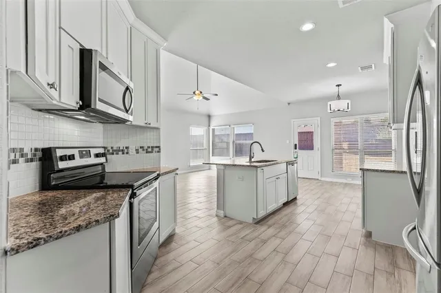 a kitchen with stainless steel appliances granite countertop a stove a sink and a refrigerator