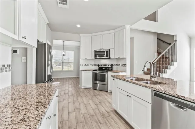 a kitchen with kitchen island granite countertop a sink cabinets and stainless steel appliances