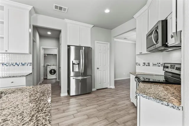 a kitchen with stainless steel appliances granite countertop a refrigerator a stove and a sink with granite countertops