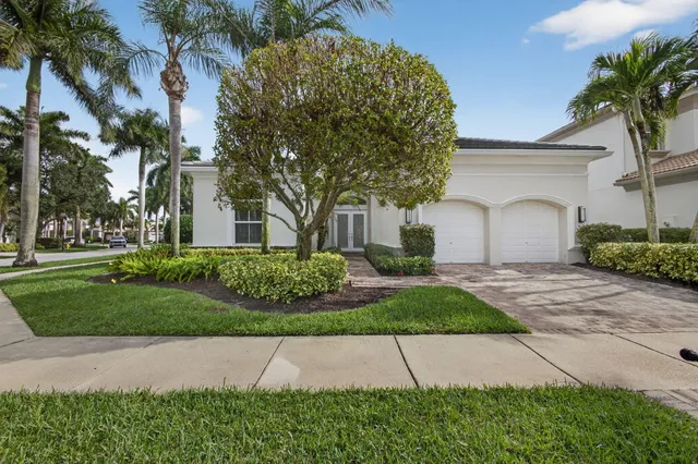 a front view of a house with a garden and palm trees