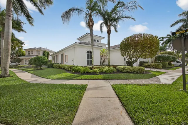 a view of a white house with a big yard and potted plants