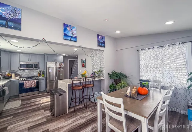 a living room with stainless steel appliances furniture a dining table and chairs in it