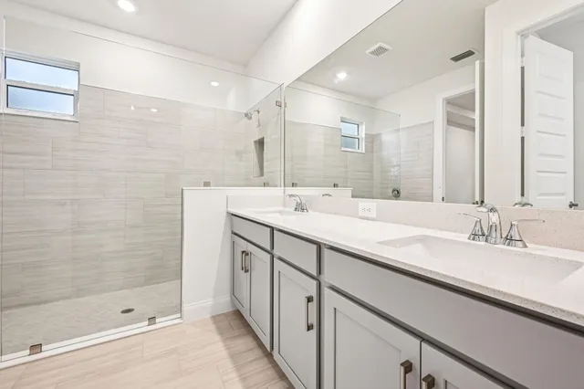a bathroom with a double vanity sink mirror and shower